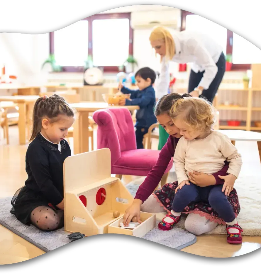 A teacher supervises children playing with educational toys in a bright, colorful preschool classroom.
