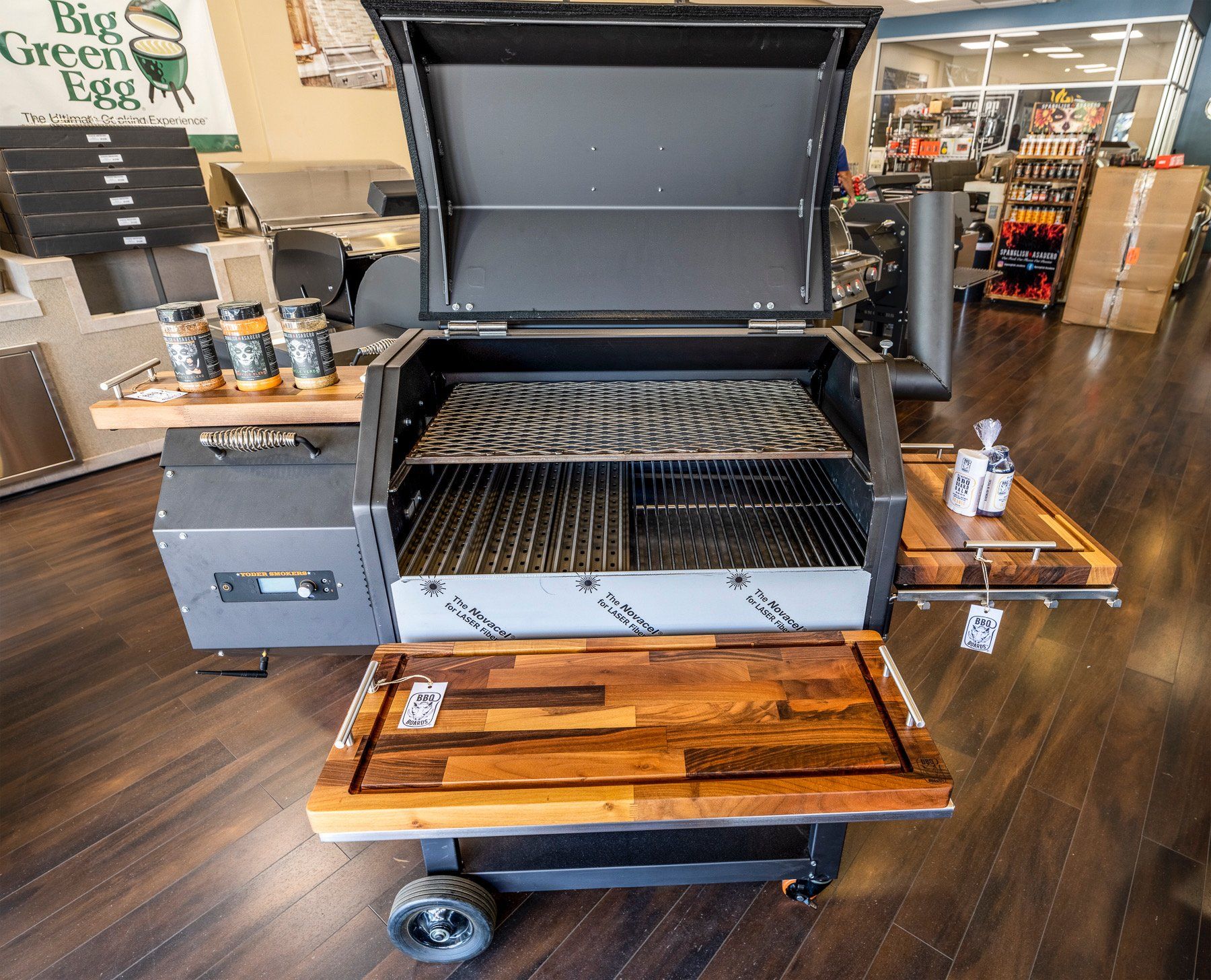 Black smoker grill with open lid, wood cutting boards, and spice bottles.