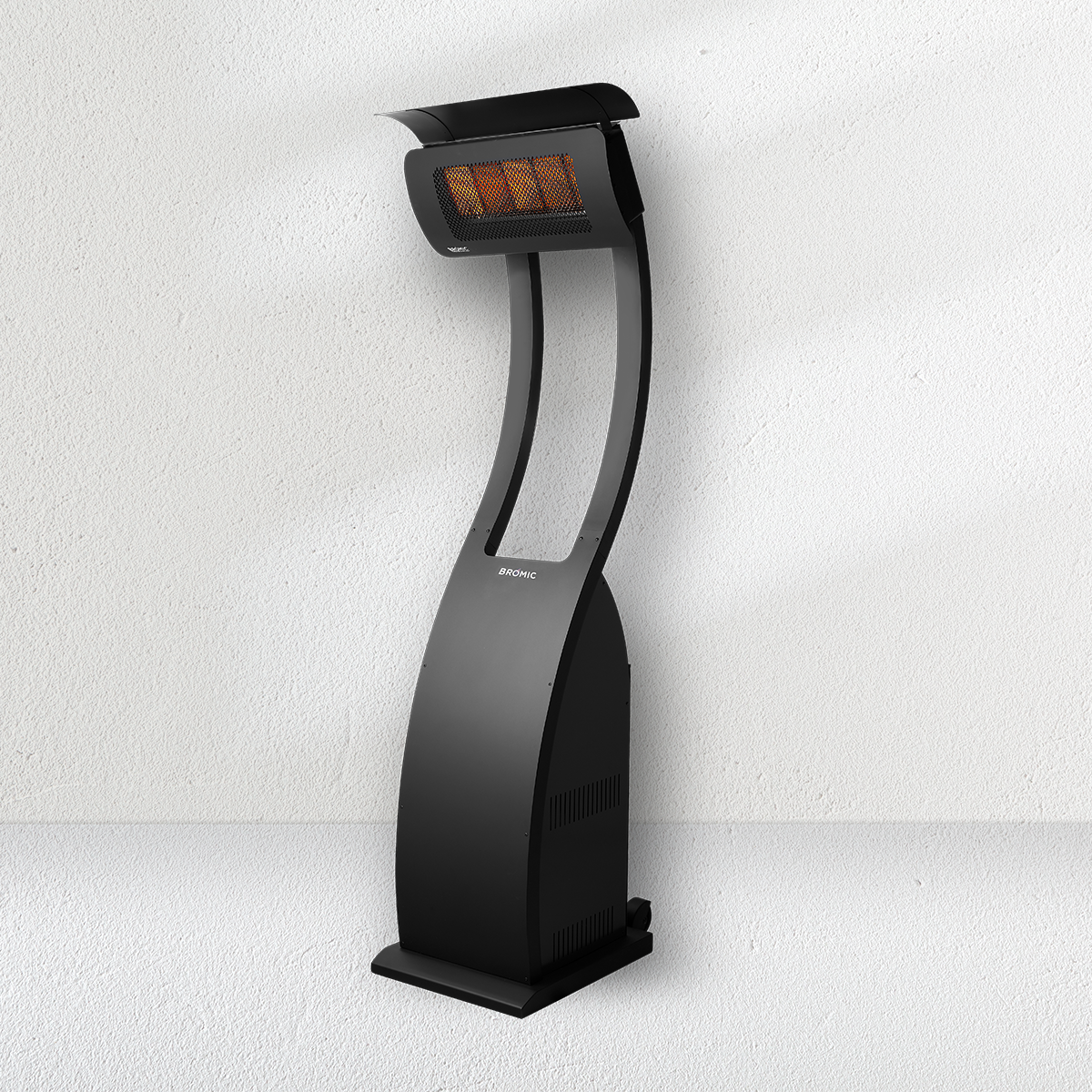 A black heater is sitting in front of a white wall.