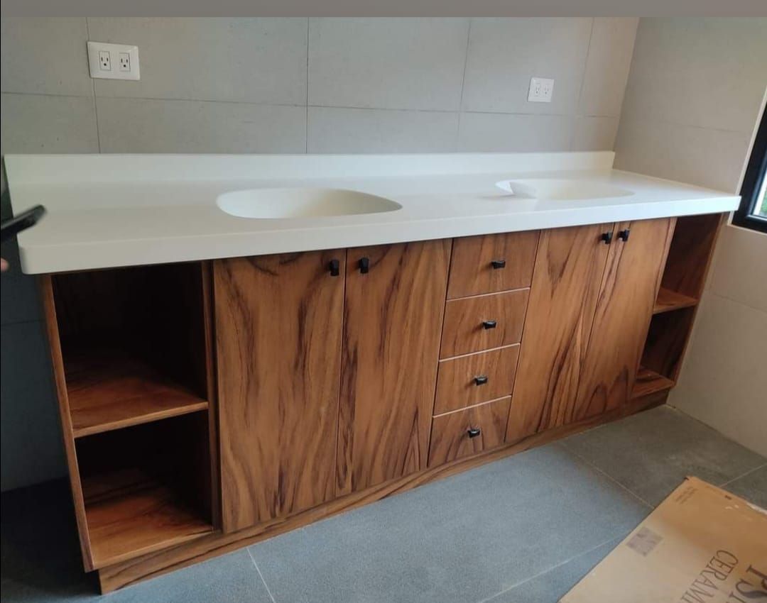 Mueble de baño de madera con encimera blanca, lavabo ovalado, estantes laterales abiertos y cajones