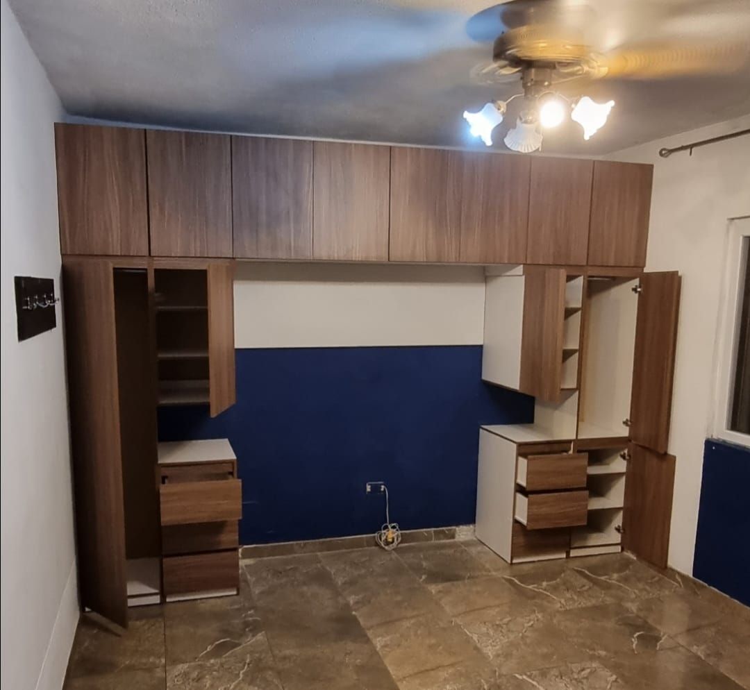 Armarios de oficina de madera empotrados con pared azul y suelo de piedra bajo una lámpara de techo.