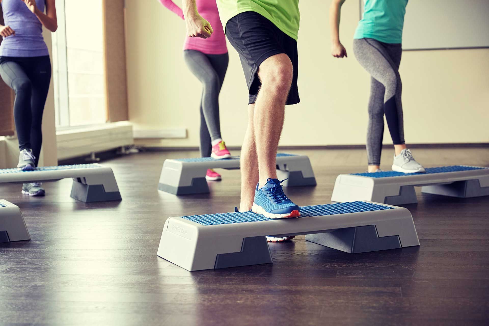 group of people flexing legs on step platforms