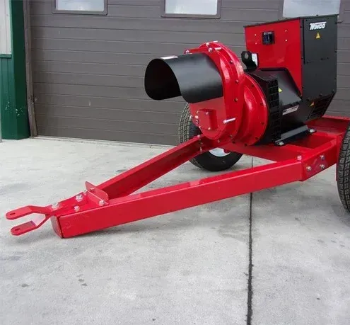 Red and black wood chipper machine on a trailer, parked outside a building.