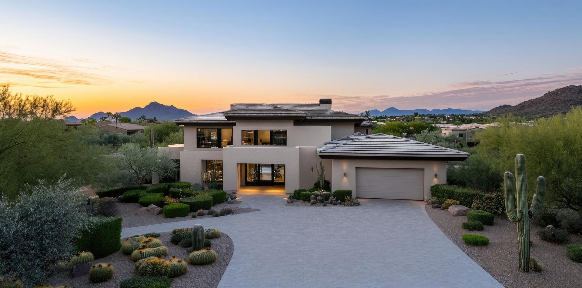 Modern desert house at sunset with a gravel driveway and mountains in the background