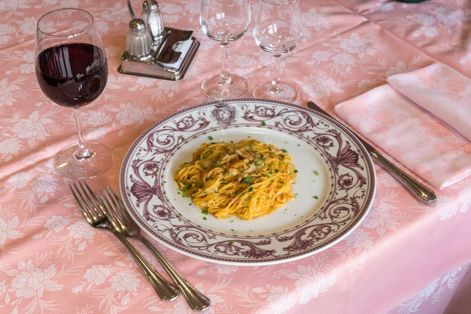 Fettine di bistecca grigliate su un piatto nero con erbe aromatiche, pomodori e spicchi d'aglio