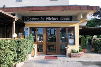 Tavolo da ristorante rustico con piatti e bicchieri in una luce calda, con uno sfondo di parete in legno.