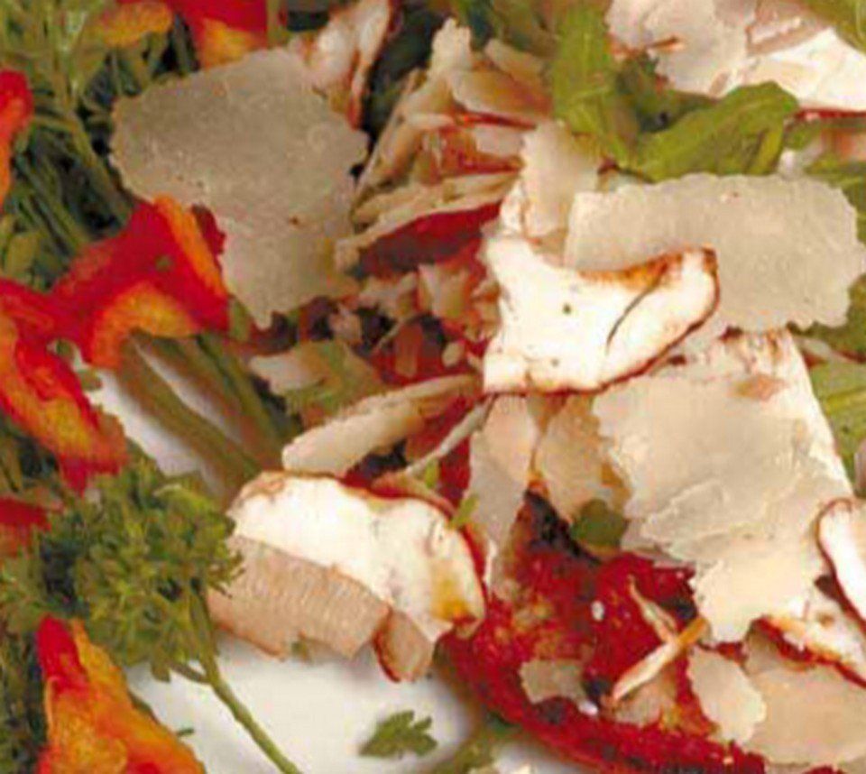 Insalata guarnita con scaglie di parmigiano, peperoni rossi e verdure.