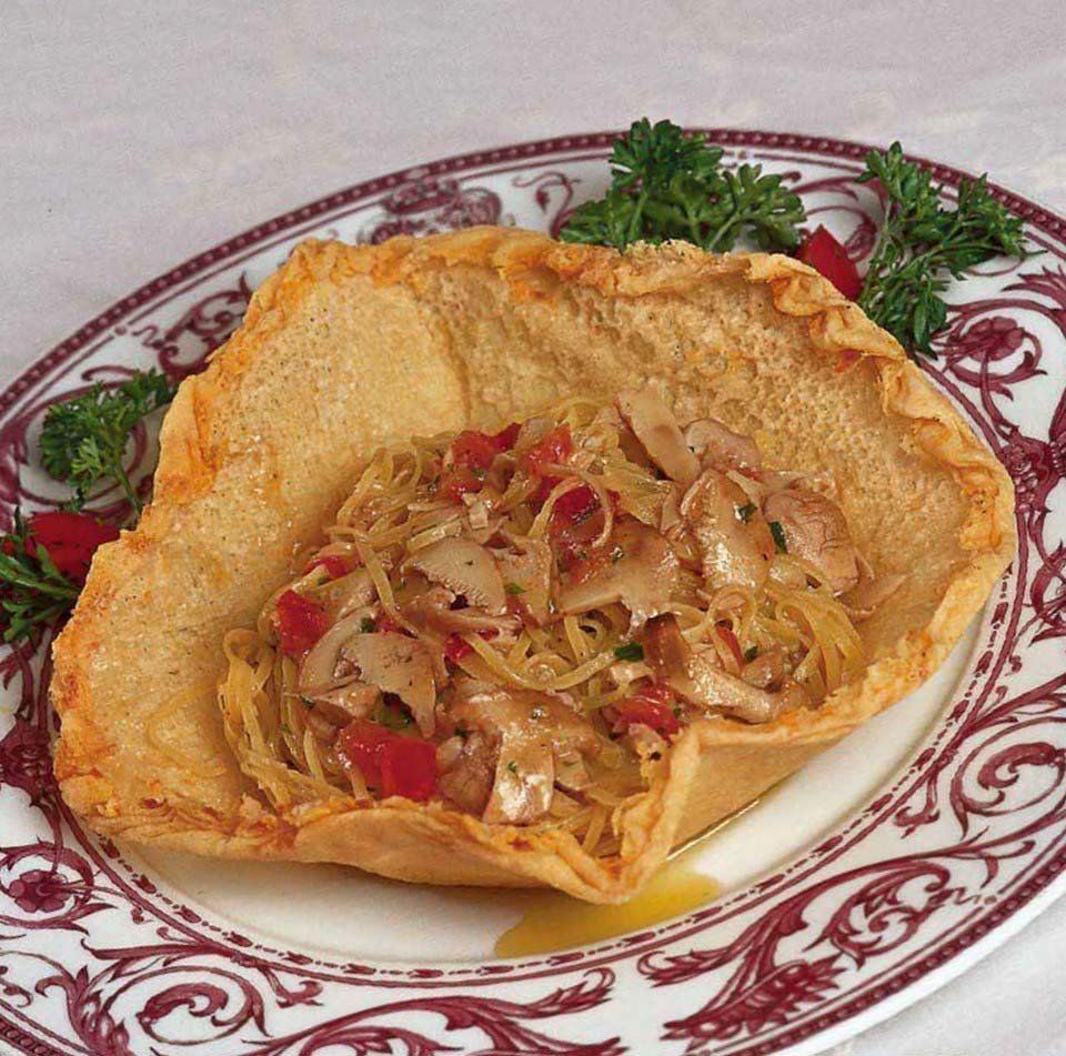 Ciotola di tortilla ripiena di insalata di mare su un piatto bianco decorativo, guarnita con prezzemolo.