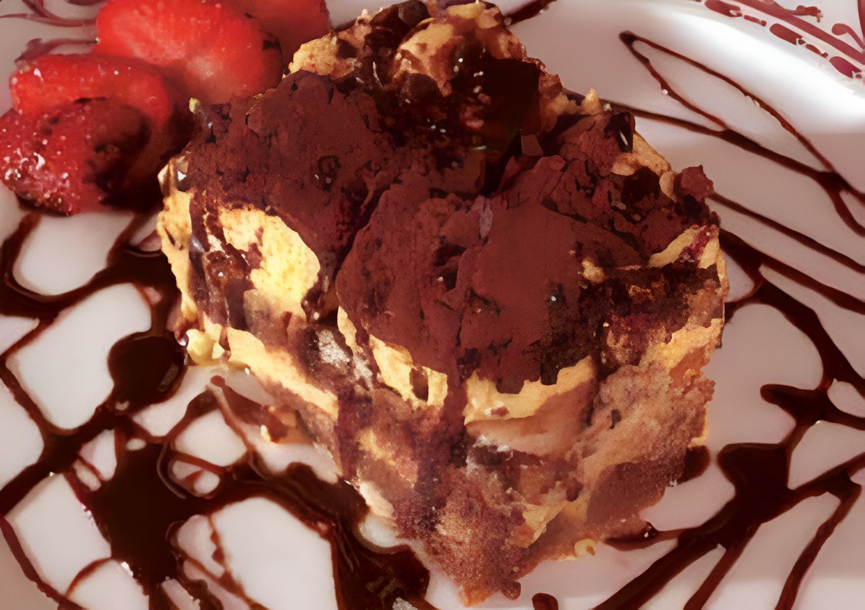 Tiramisù al cioccolato con salsa, servito su un piatto bianco con fragole.