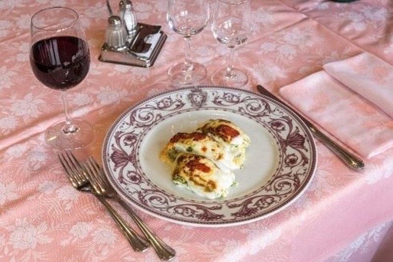 Costolette di maiale arrosto con crosta croccante, patate e verdure su un piatto bianco.