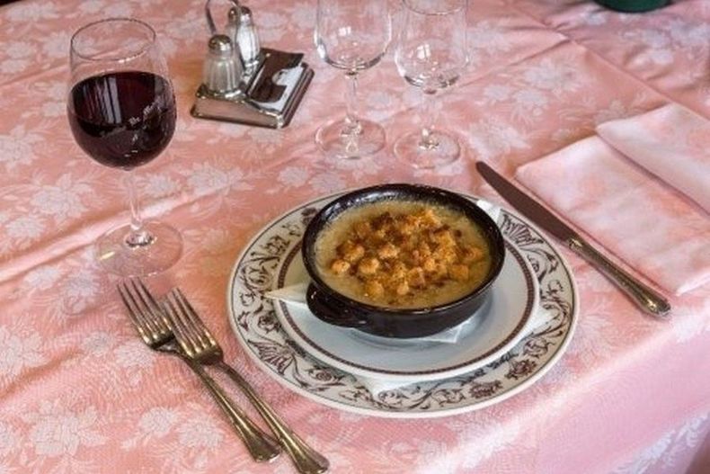Mani che stendono la pasta fresca su un piano di lavoro infarinato in cucina.