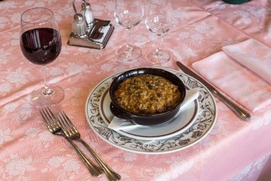 Fettine di bistecca grigliate su un piatto nero con erbe aromatiche, pomodori e spicchi d'aglio