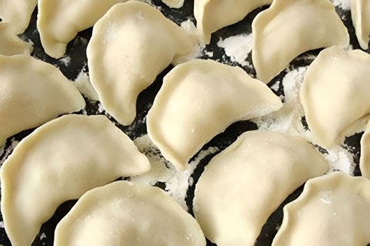 Primo piano di ravioli di pasta ripieni crudi con ripieno cremoso su una superficie scura