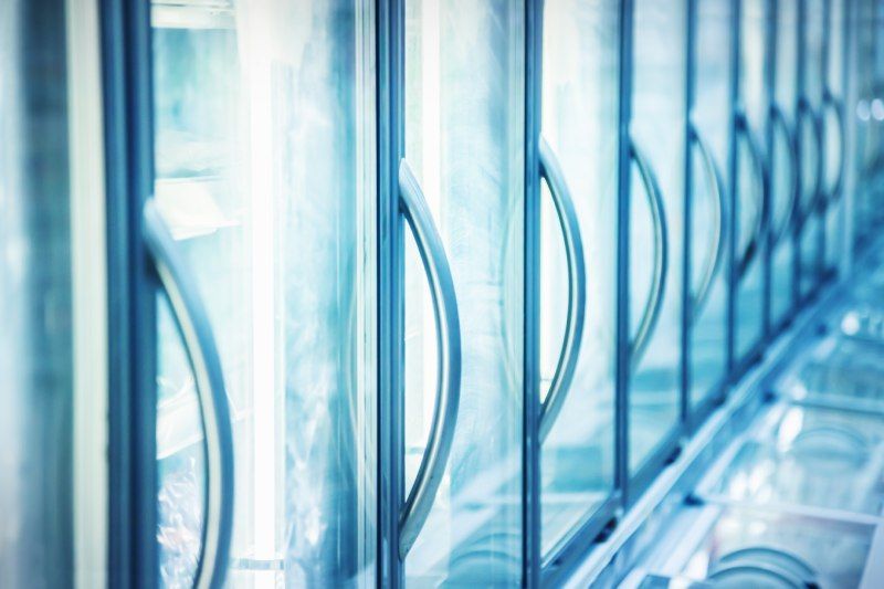 A row of glass doors in a refrigerator in a store.