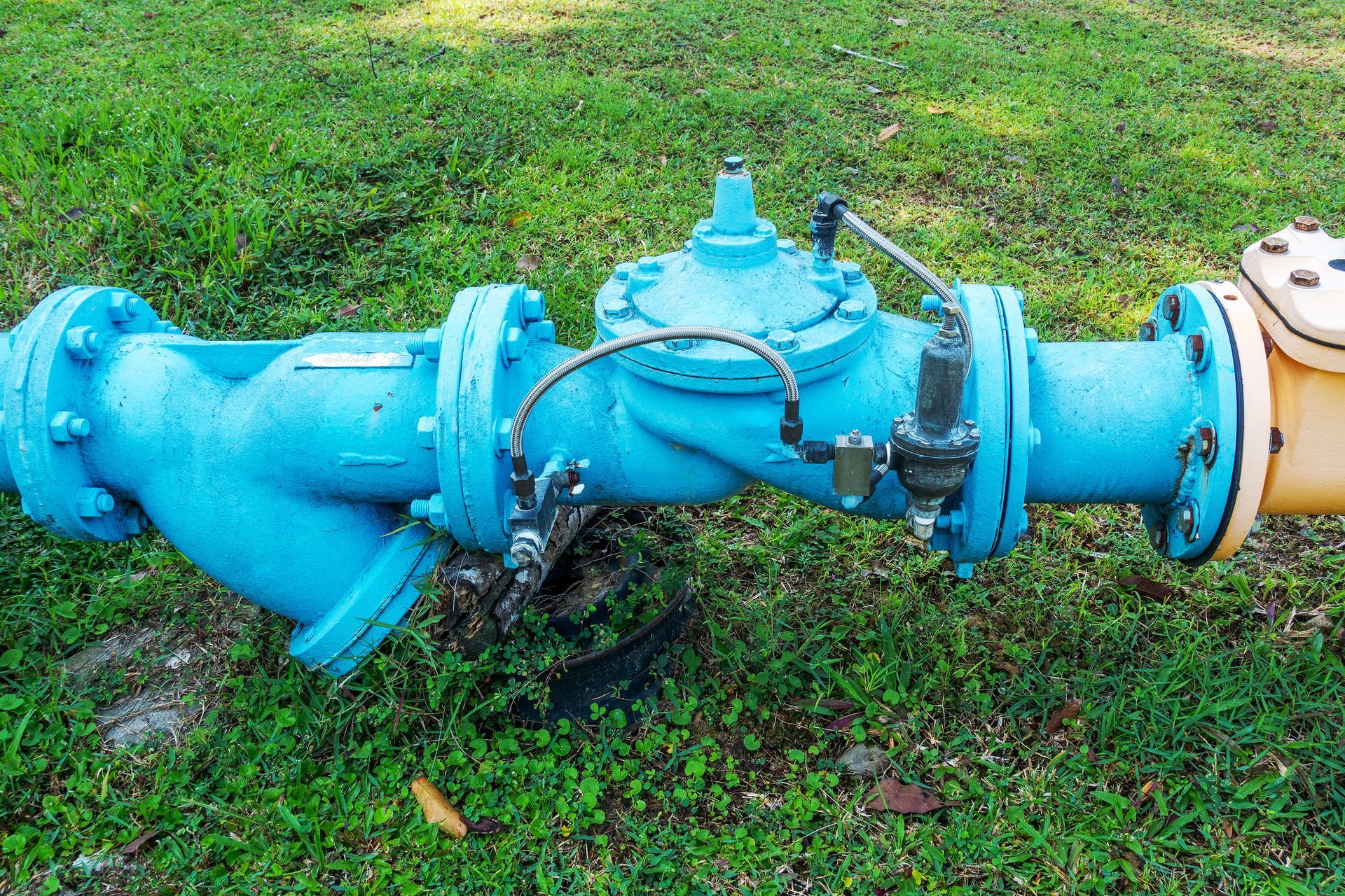 Blue water pipe with attached gauges and yellow pipe on grass. Blue water pipe with attached gauges and yellow pipe on grass.