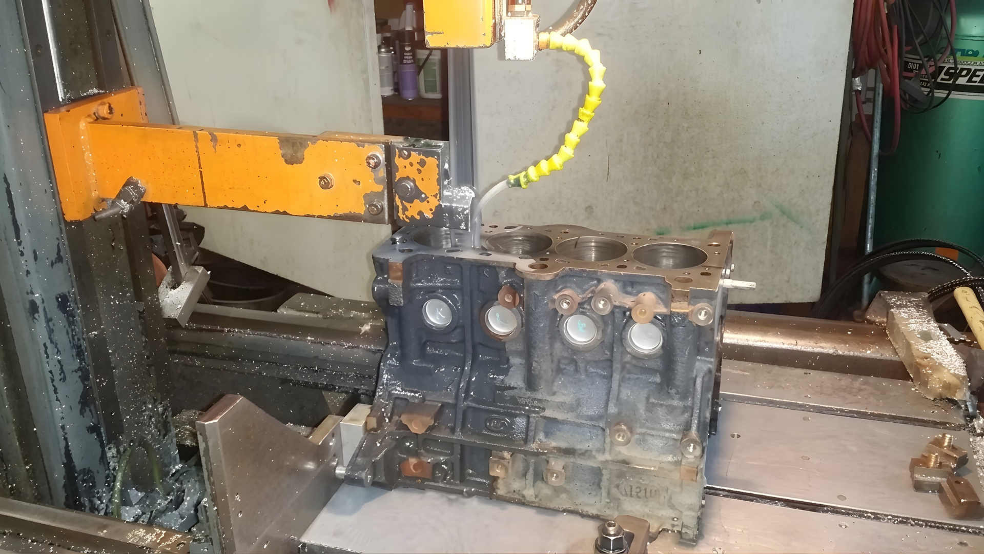 Industrial machine with orange arm and dark metal component in a workshop setting