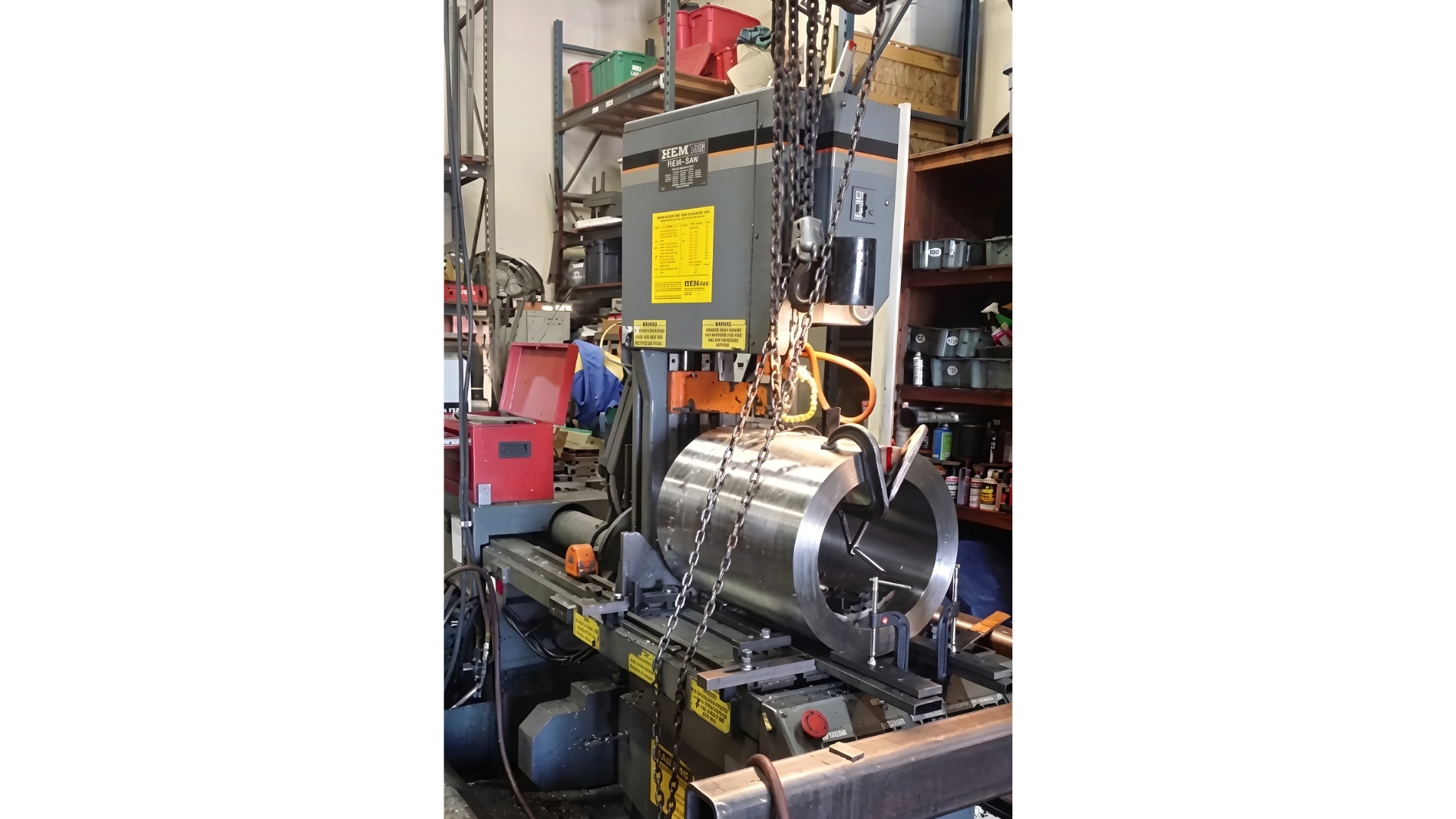 Industrial workshop with a shiny metal machine mounted on a rack, surrounded by tools and equipment.