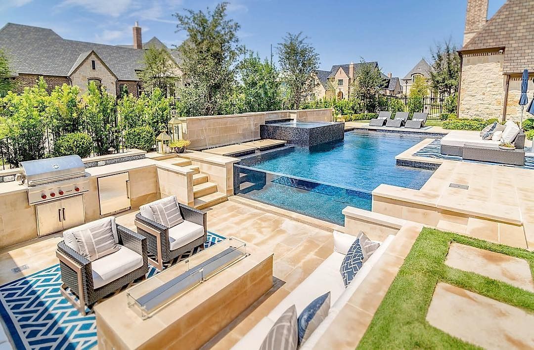 Luxury backyard pool with stone patio, lounge seating, and blue water under a clear sky