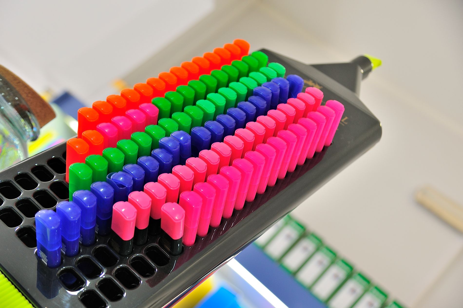 File di pennini colorati, arancione, verde, blu, rosa, su un evidenziatore nero.