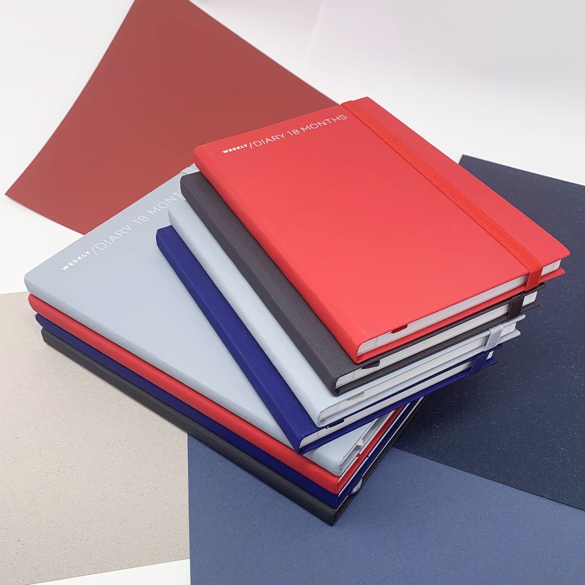 Pila di quaderni colorati con elastico rosso.