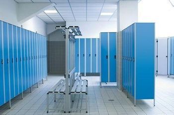 Gli armadietti blu fiancheggiano uno spogliatoio con panchine e illuminazione dall'alto.