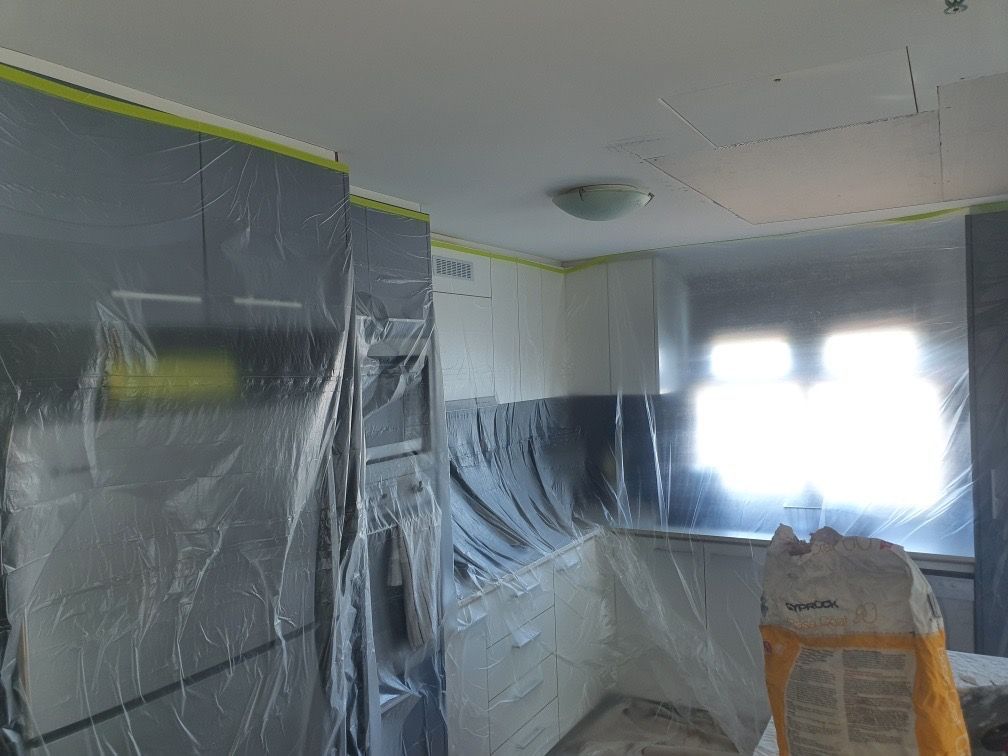 Kitchen interior undergoing renovation. Cabinets and surfaces covered in gray plastic for protection — Patch Plaster Paint in Johnston, NT