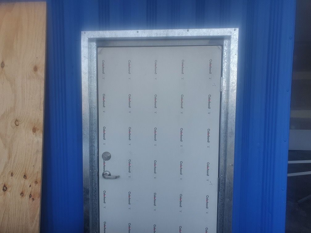 Blue exterior door with a metal frame and white paneling — Patch Plaster Paint in Johnston, NT
