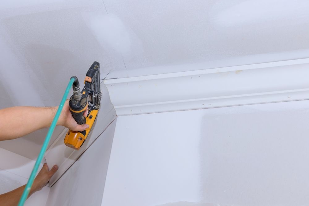 Person Uses a Nail Gun to Install Crown Molding — Patch Plaster Paint in Johnston, NT