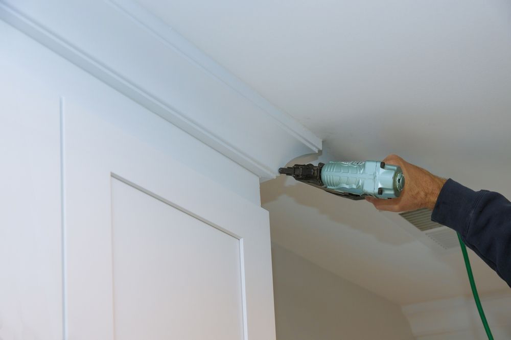 Person Using a Nail Gun to Install White Crown Molding — Patch Plaster Paint in Johnston, NT