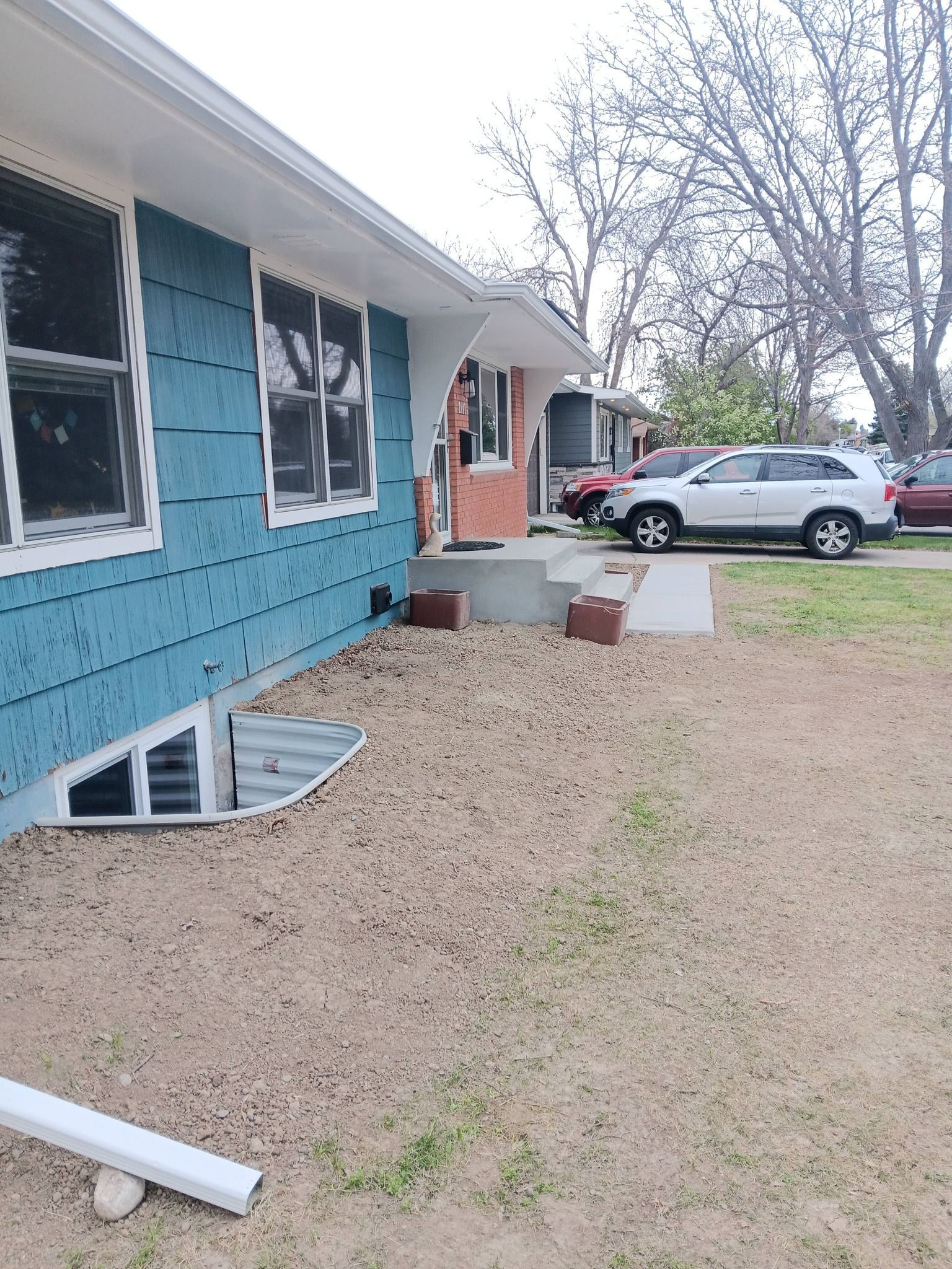 Teal house exterior with damaged basement window and a white SUV parked in the yard.