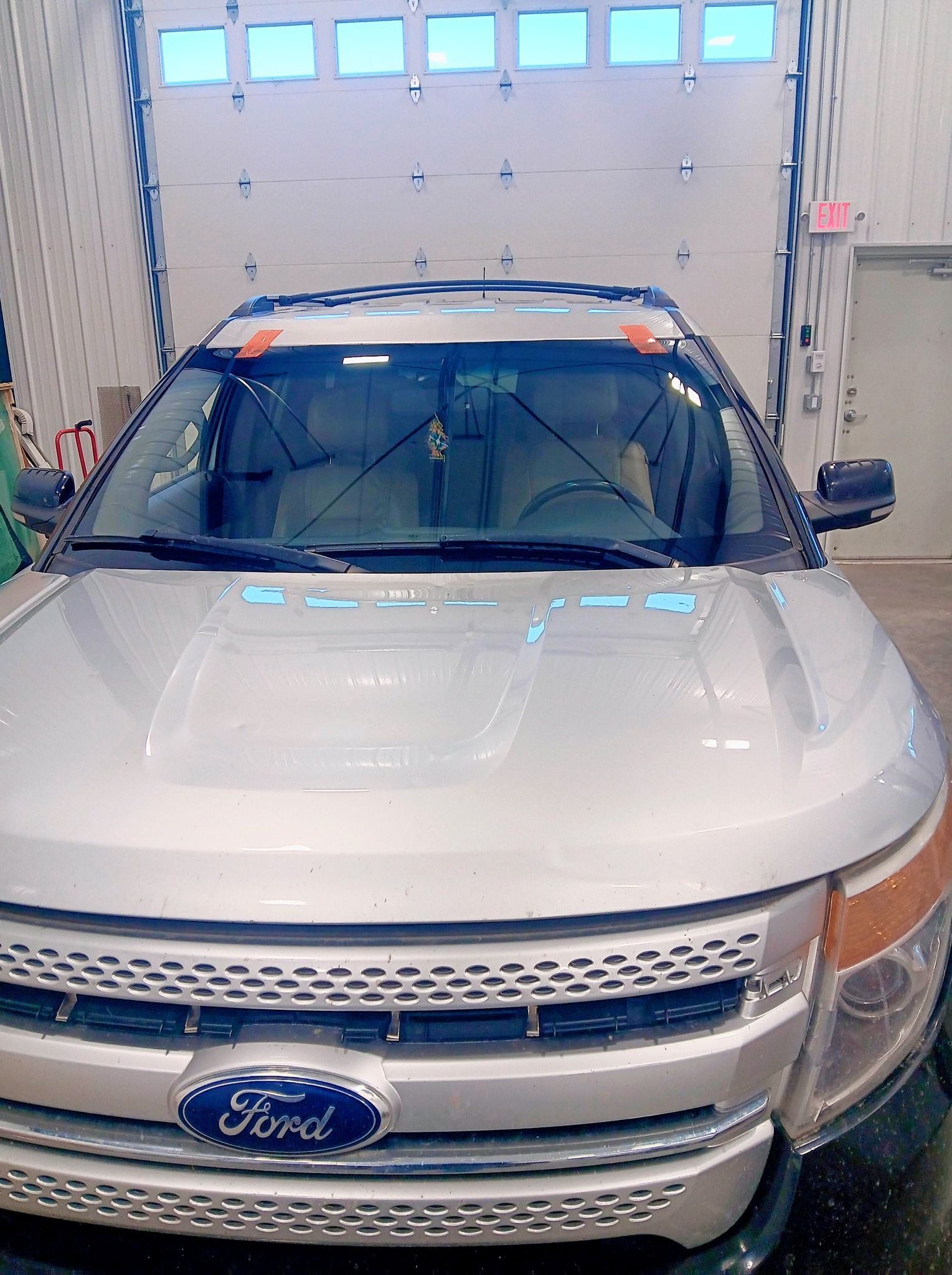 White Ford SUV parked inside a garage bay with a closed overhead door in the background