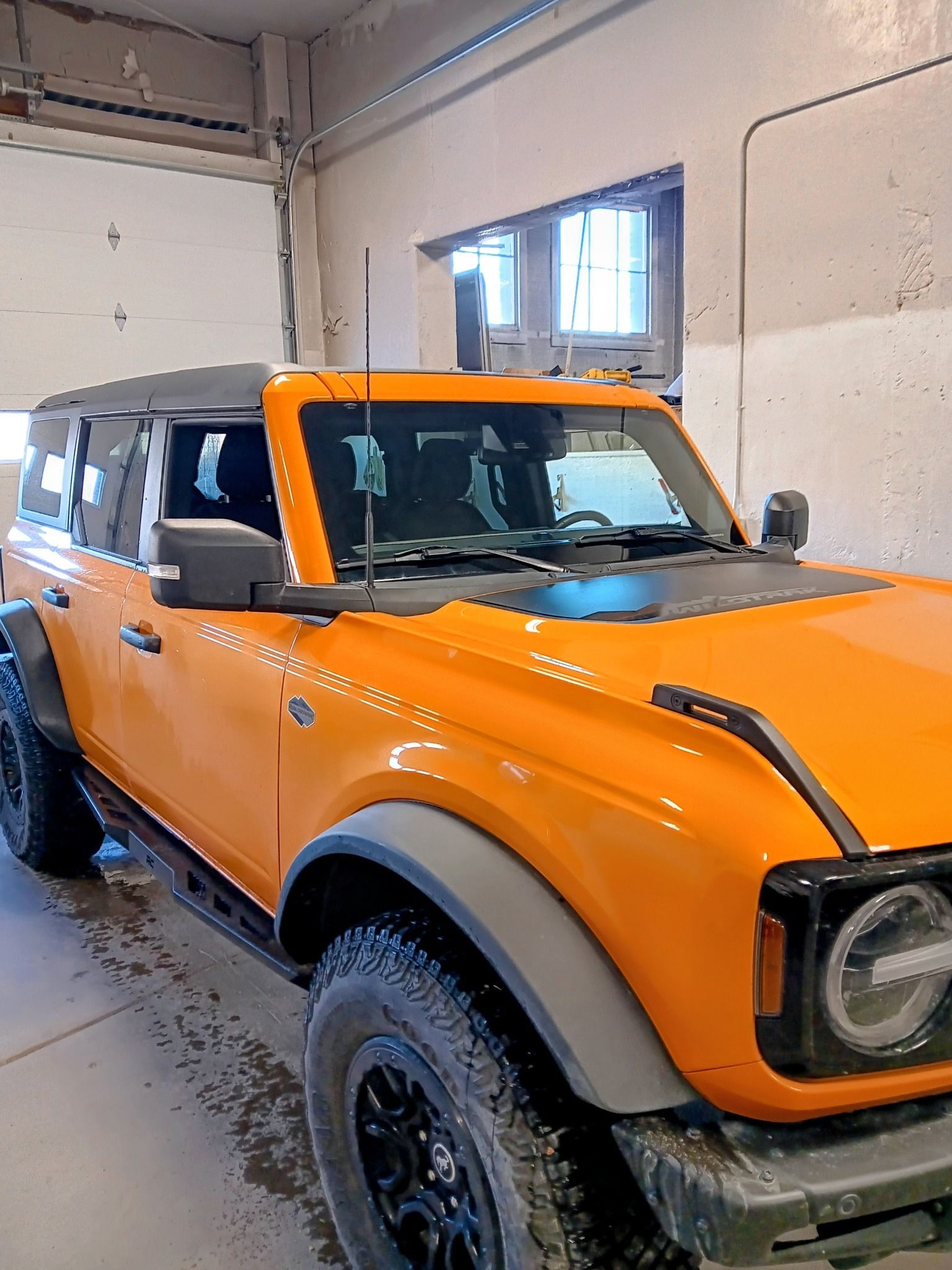 Orange off-road SUV parked indoors in a garage, front-left view