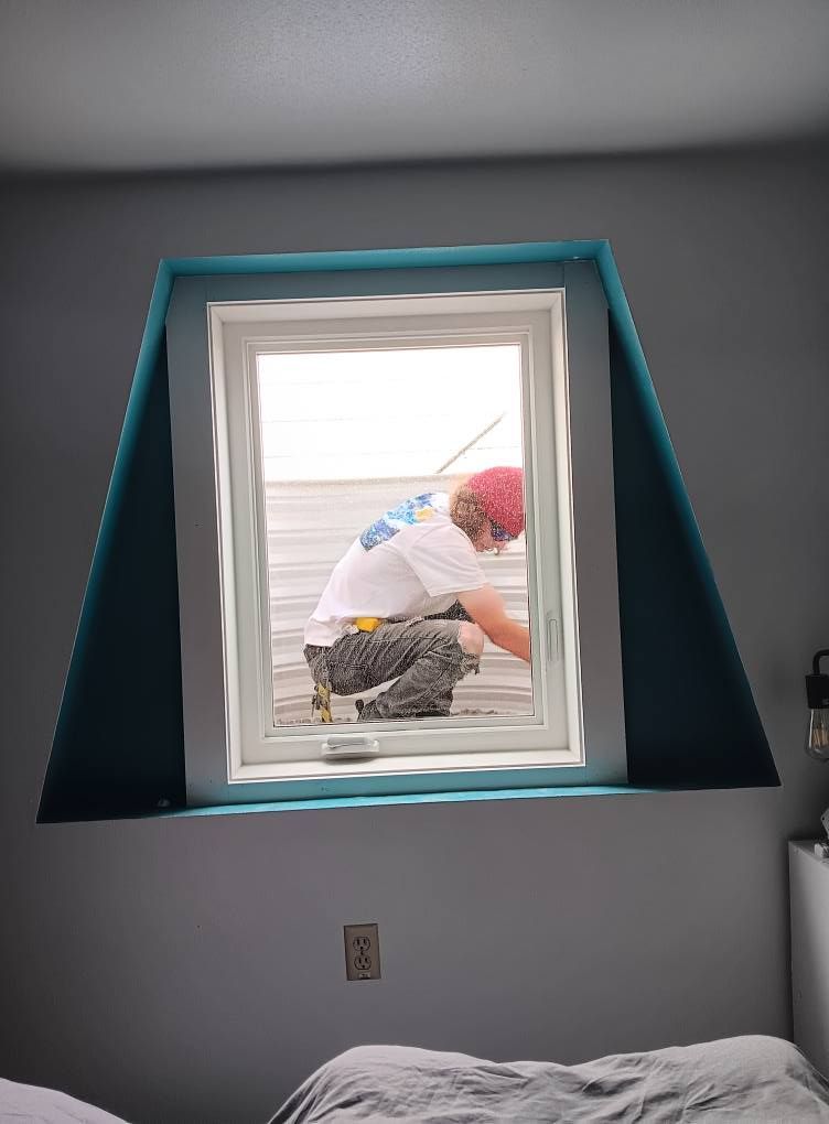 Person kneeling outside a window frame in a gray room with teal trim on the window alcove