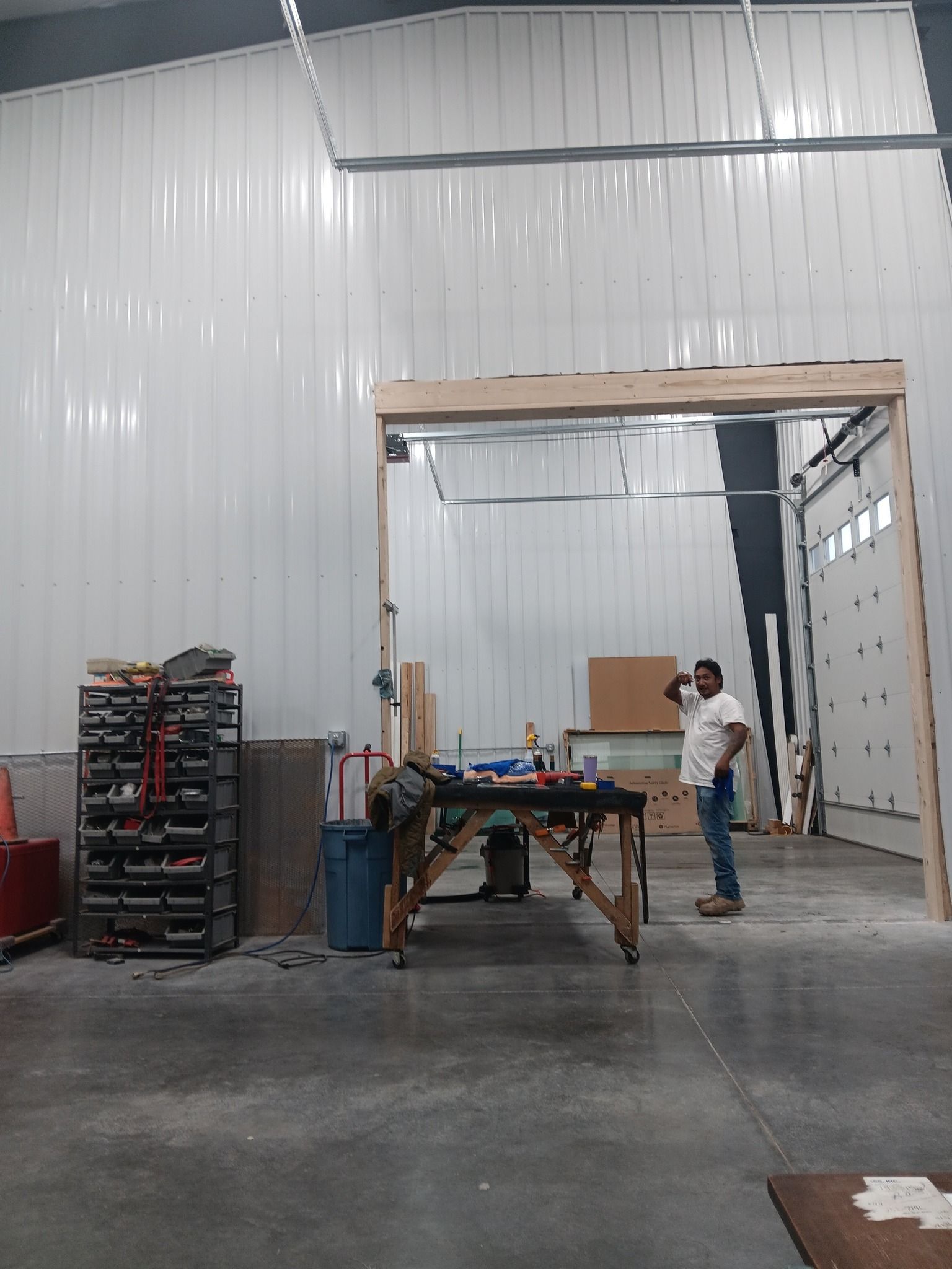 Warehouse interior with two people working beside a wooden frame and stacked crates on a concrete floor.