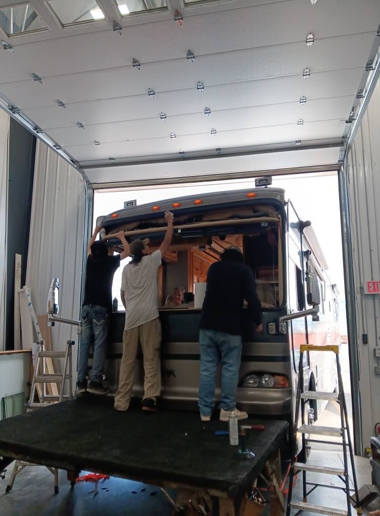 Two people unloading a van on a lift platform inside a garage-like bay