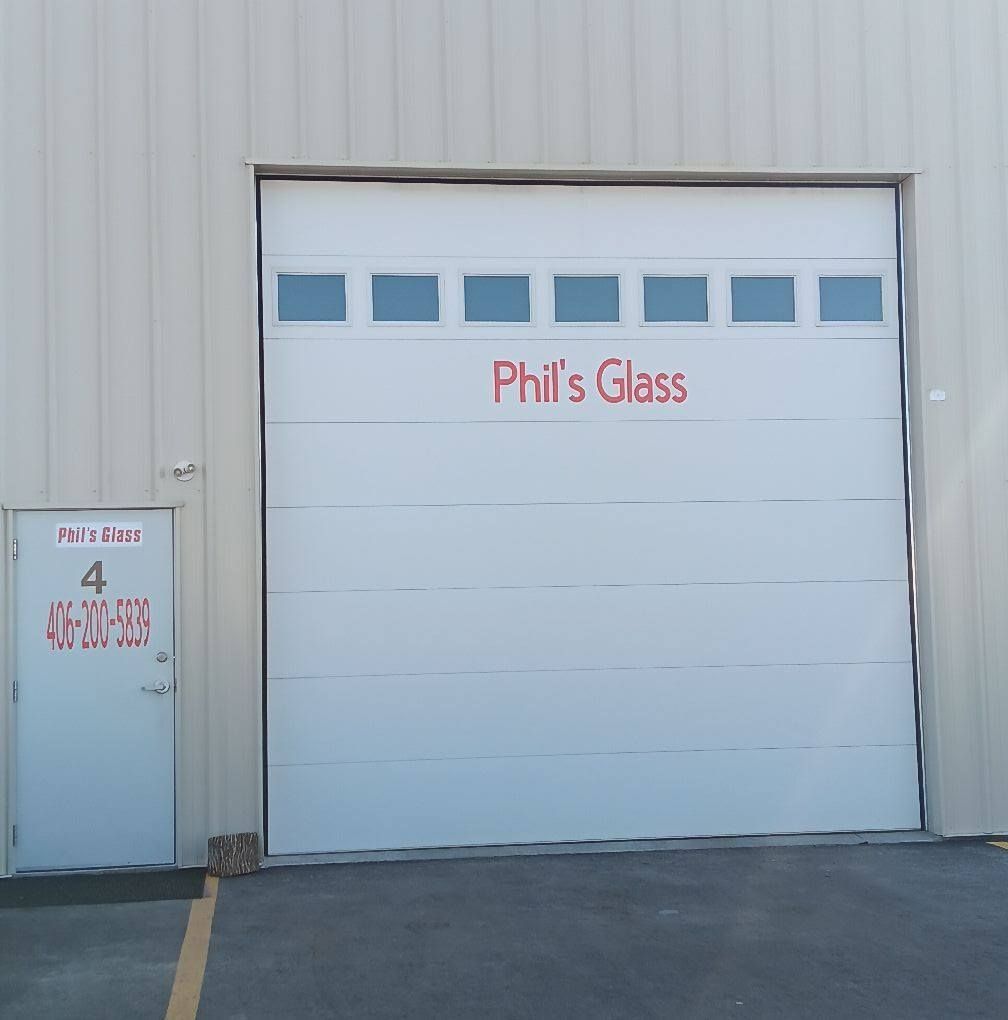 Phil’s Glass storefront with a white garage door and small side entry door.