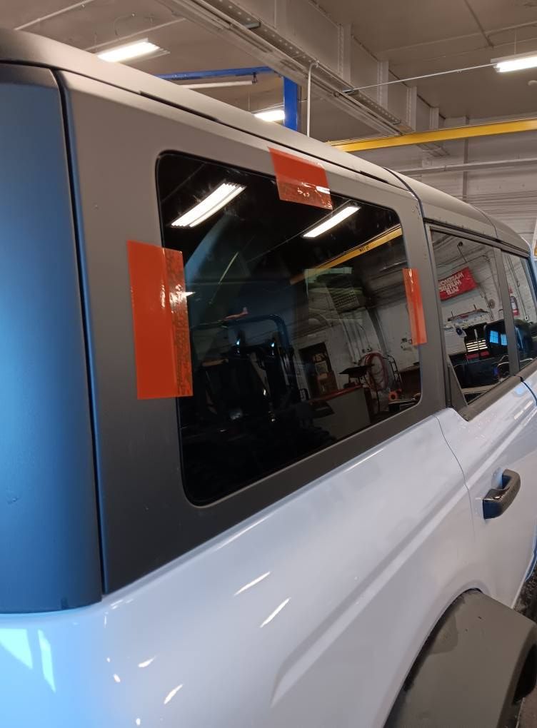 White SUV in a garage, showing the side windows with orange protective tape and a closed door.
