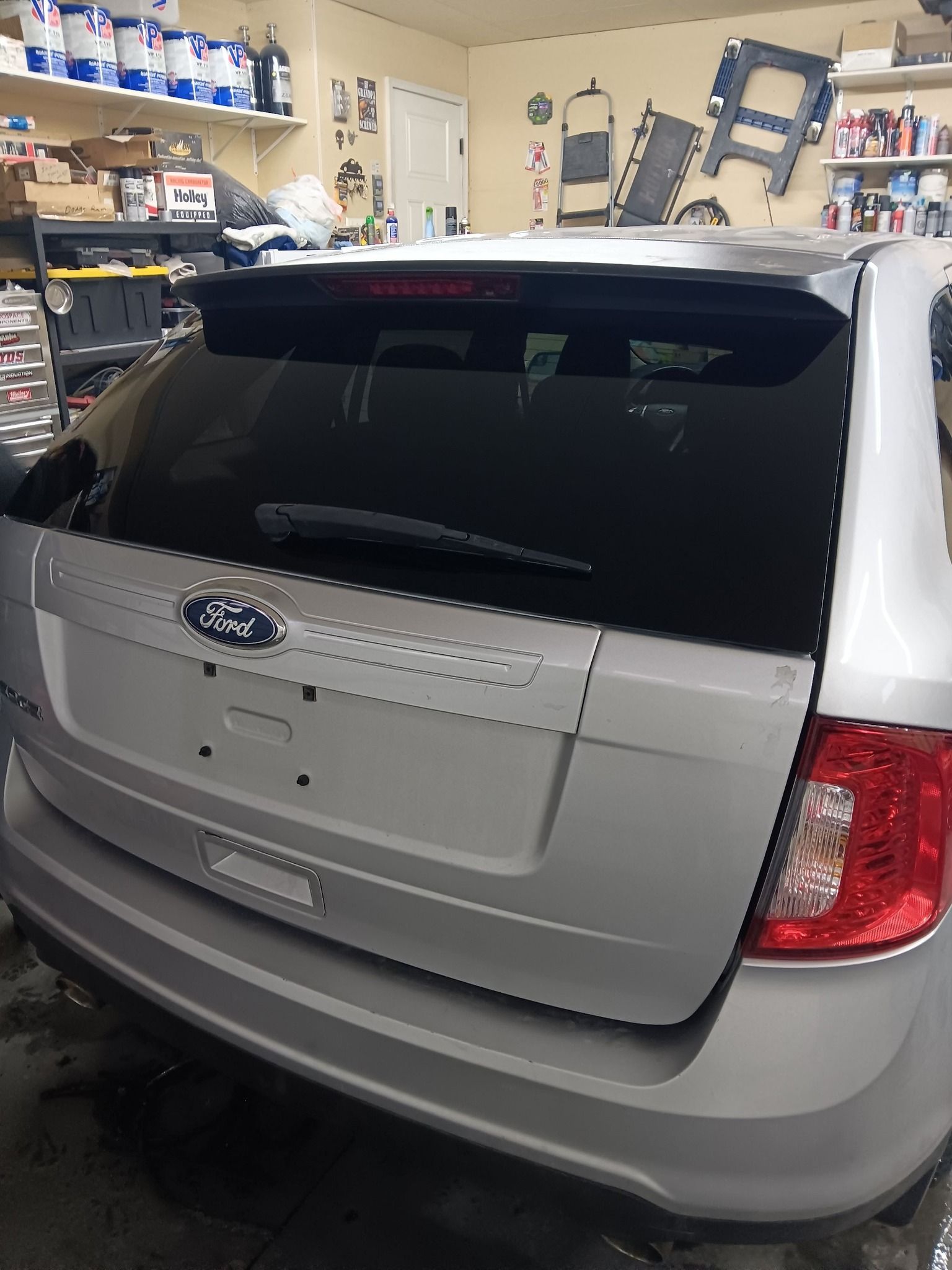 Silver Ford SUV parked in a garage, rear view with dark tinted windows.