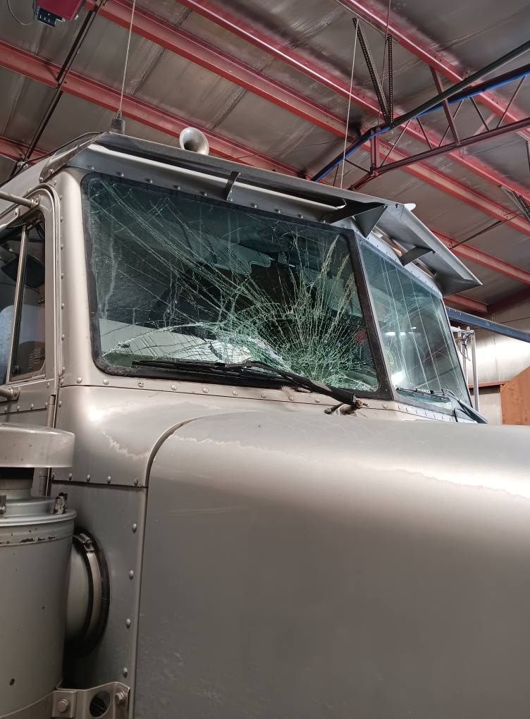 Cracked truck windshield in a garage, with red roof beams overhead