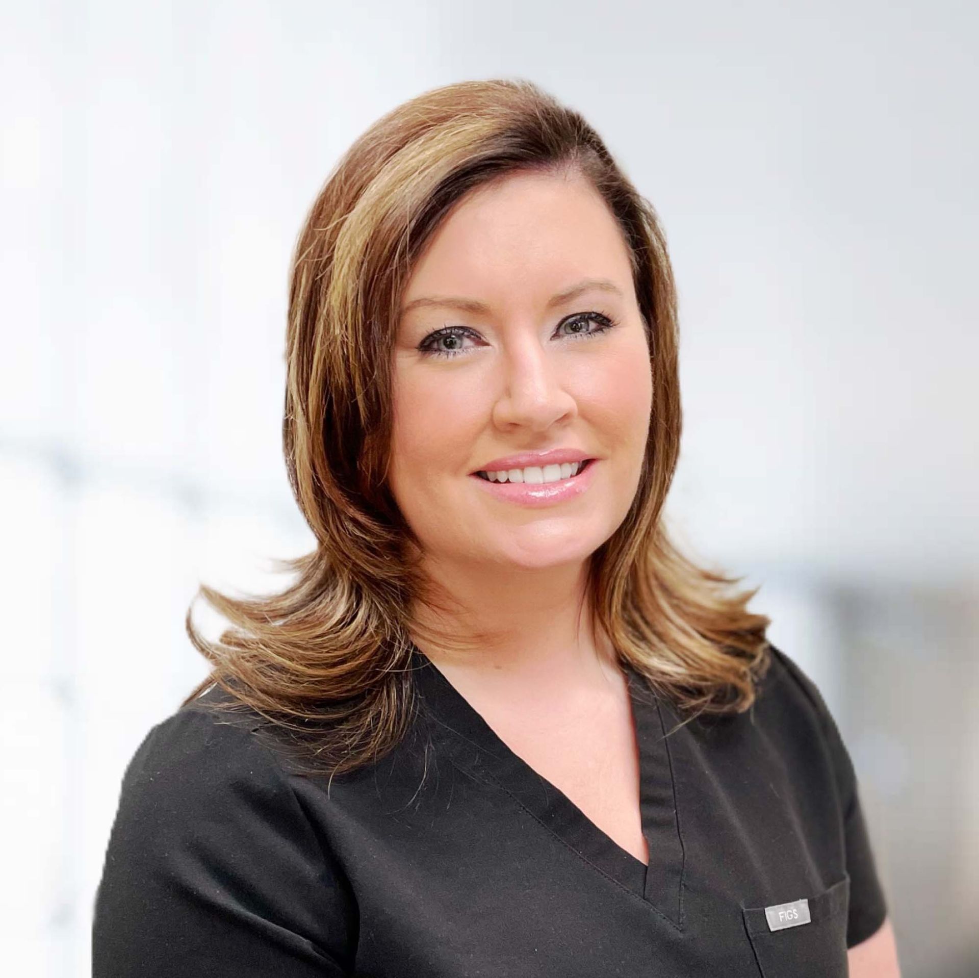A woman in a black scrub top smiles for the camera