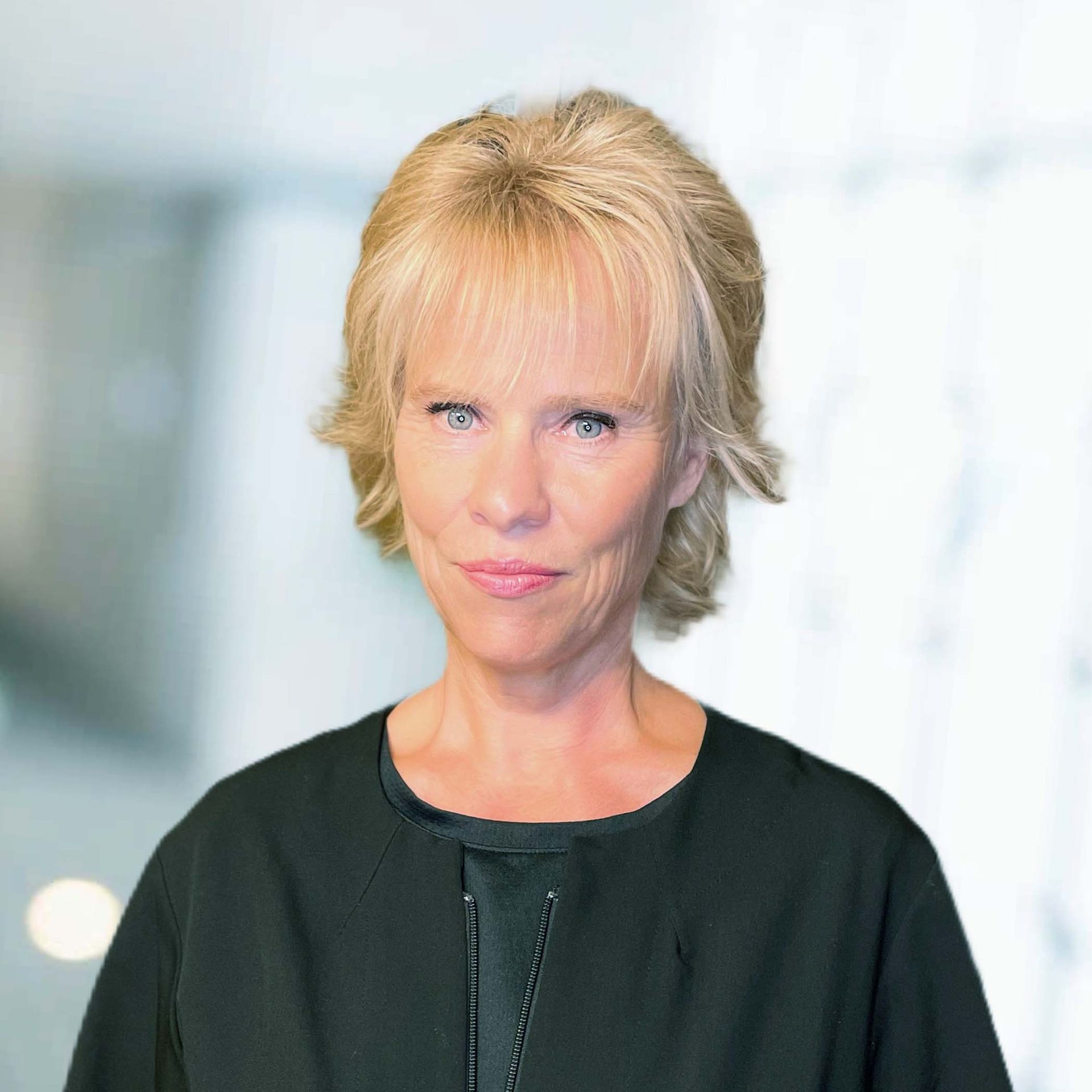 A woman with blonde hair is wearing a black shirt and looking at the camera.
