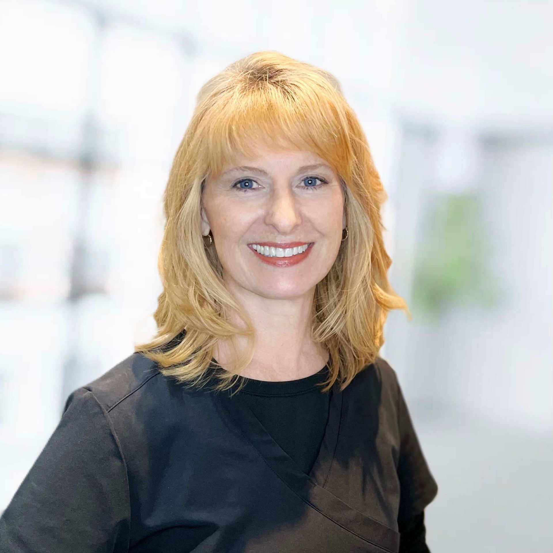 A woman with blonde hair and a black shirt is smiling for the camera.