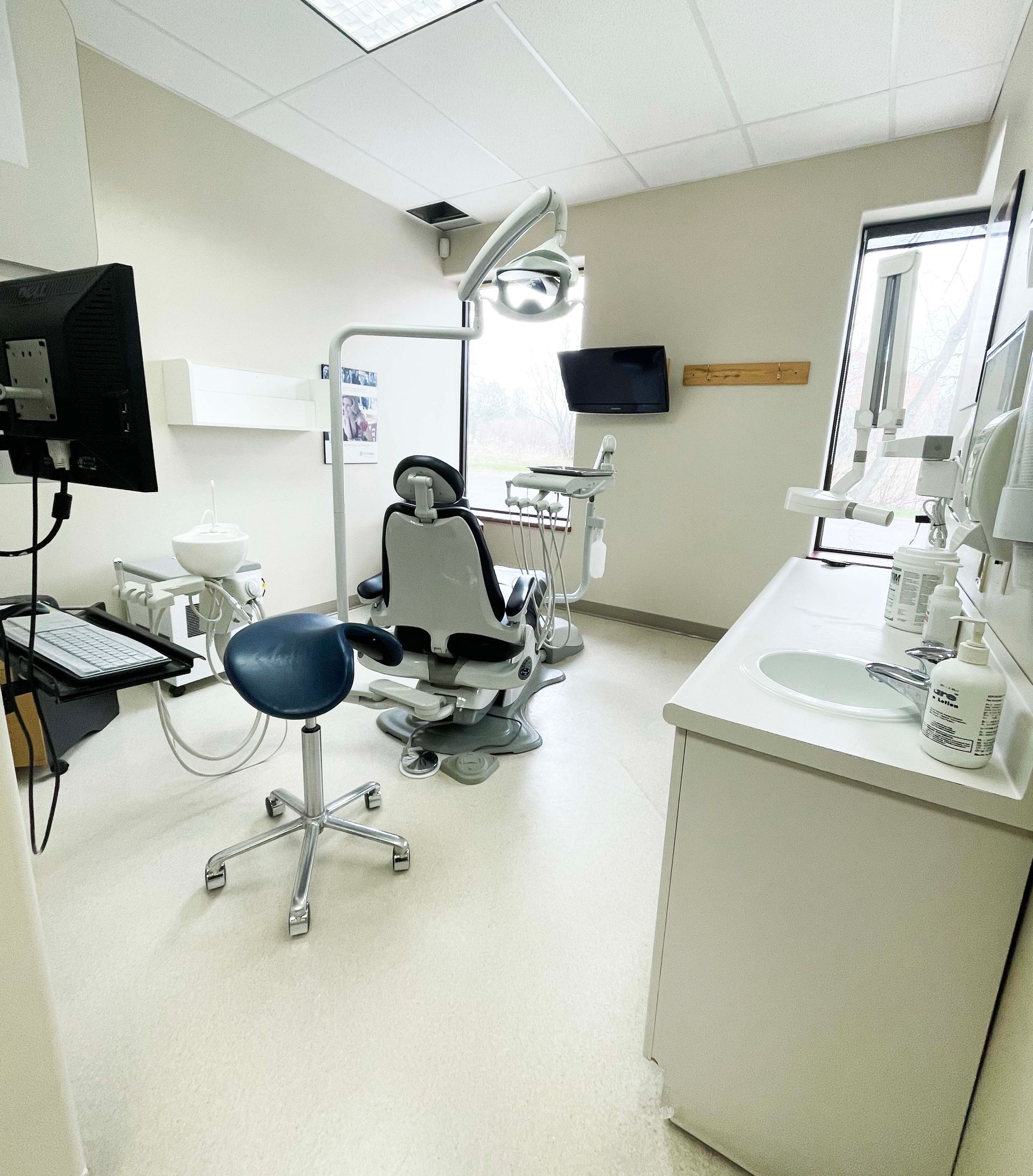A dental office with a dental chair and a monitor