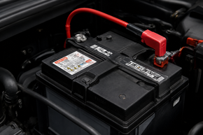 Close-up of a car battery with red positive cable connected in the engine bay