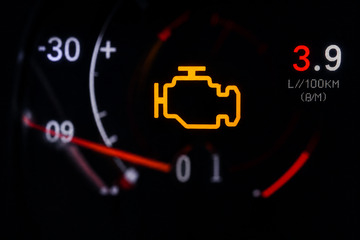 Car dashboard showing a check engine warning and fuel economy gauge reading 3.9 L/100 km