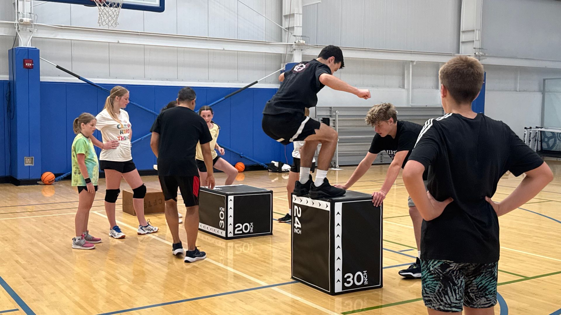 Kids doing box jumps in a gym during a training session