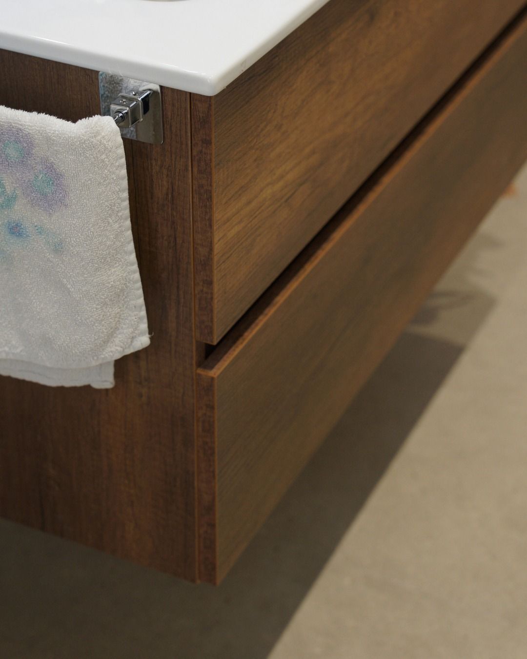 Cassettiera in legno con due cassetti e piano d'appoggio bianco, parzialmente rivestito da un panno.