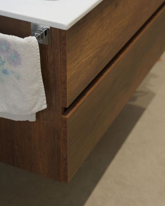 Cassettiera in legno con due cassetti e piano d'appoggio bianco, parzialmente rivestito da un panno.