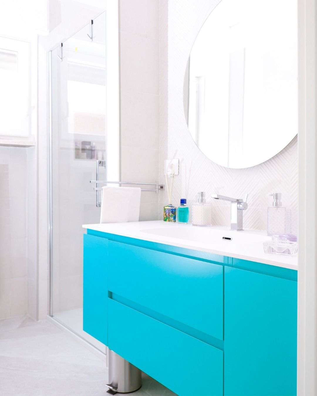 Luminoso bagno in marmo con vasca freestanding, finestra, mobile lavabo e cornice dello specchio turchese.