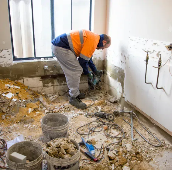 A man in an orange shirt is working on a wall